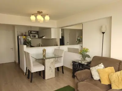 a living room with a table and a kitchen at Departamento Costa Verde San Miguel in Lima