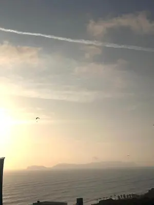 a bird flying in the sky over the ocean at moderno departamento con vista al mar en miraflores in Lima
