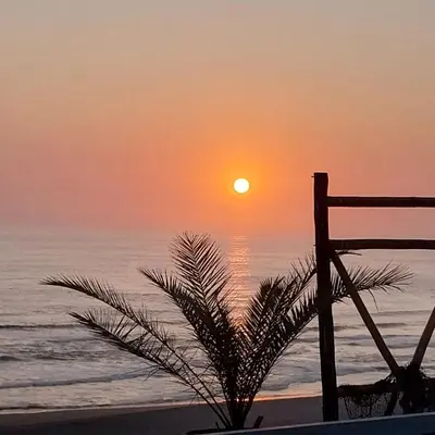 a sunset on the beach with a palm tree at Linda Casa de playa con vista al mar de Wakama in Jaguay