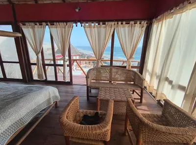 a bedroom with a bed and chairs and windows at Linda Casa de playa con vista al mar de Wakama in Jaguay