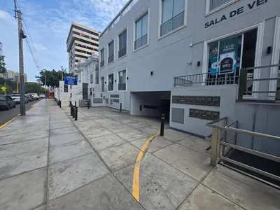 a white building on a sidewalk next to a street at Apartment overlooking the water park in Lima