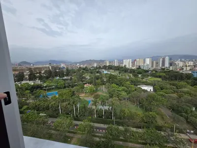 a view of a city with buildings and trees at Apartment overlooking the water park in Lima