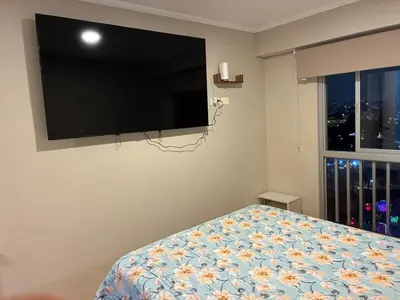 a bedroom with a flat screen tv and a bed at Spacious downtown apartment overlooking Parque de las Aguas in Lima