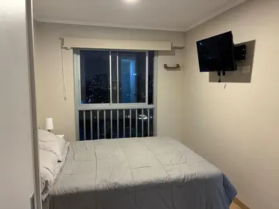 a bedroom with a bed and a window with a view at Spacious downtown apartment overlooking Parque de las Aguas in Lima