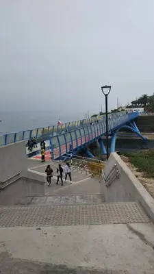 a group of people walking on a bridge near the ocean at Barranco sea in Lima