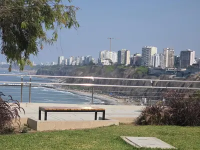 a bench sitting next to a beach with a city at Barranco sea in Lima