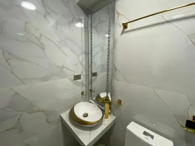 a white bathroom with a toilet and a sink at Hotel Sonccollay in Huancayo