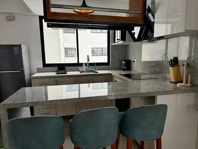 a kitchen with a counter with four green chairs at Departamento Vizuale in Lima