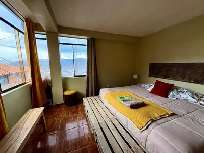 a bedroom with a bed with a bench and large windows at New colorful & artsy home, fam perfect, great wifi for working in Cusco