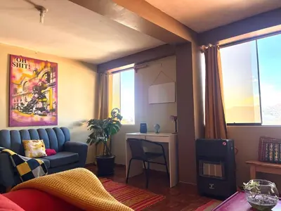 a living room with a blue couch and a desk at New colorful & artsy home, fam perfect, great wifi for working in Cusco