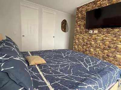 a bedroom with a bed and a tv on a brick wall at Dpto exclusivo en San Miguel con piscina y gym in Lima