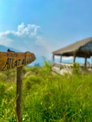 a wooden sign in the grass next to a building at Altares de Oxapampa in Oxapampa