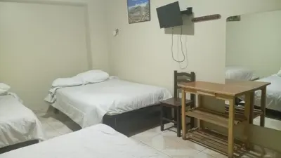 a room with two beds and a table in it at Hospedaje El Encanto in Huancayo