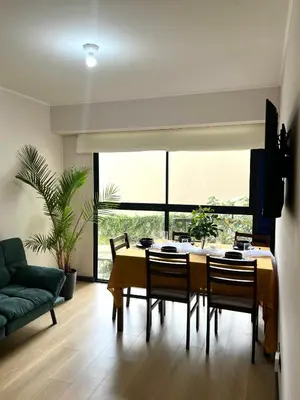 a dining room with a table and chairs and a couch at Departamento 9 Personas San Isidro in Lima