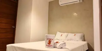 a room with a bed with white sheets and towels at Los Pulpos in Bombiso