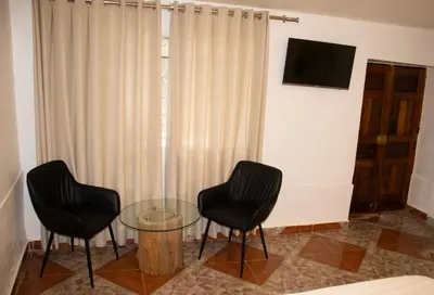 two black chairs and a glass table in a room at Xaxa Lodge in Tarma