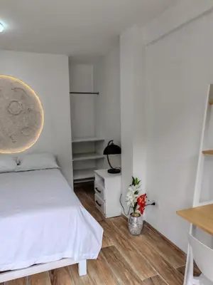 a white bedroom with a bed and a night stand at Xaxa Lodge in Tarma