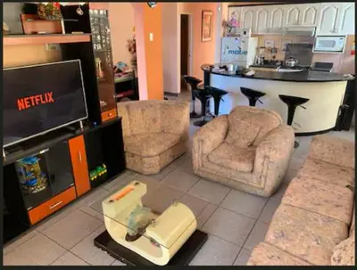 a living room with a tv and chairs and a table at Encanto azul Jardín, Parrilla y juegos in Santa Rosa
