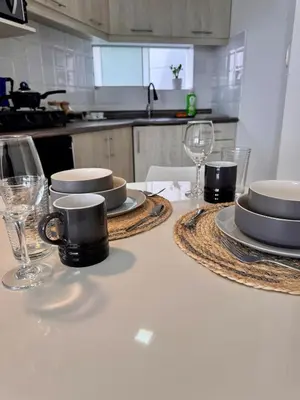 a kitchen with a table with plates and wine glasses at Alojamiento moderno San Isidro Pet Friendly in Lima