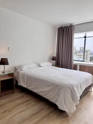 a bedroom with a white bed with a window at Alojamiento moderno San Isidro Pet Friendly in Lima
