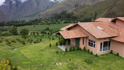 a house in a field with mountains in the background at Urubamba Luxury Stay 