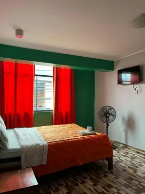 a bedroom with a bed with red curtains and a fan at Hotel PRADO'S in Satipo