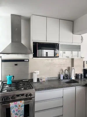 a kitchen with white cabinets and a stove top oven at Duplex penthouse in Miraflores with terrace in Lima