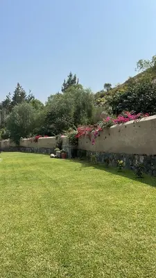 a garden with pink flowers on a stone wall at Casa de Campo en Cieneguilla in Cieneguilla