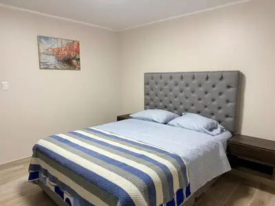 a bedroom with a bed with a blue and white striped blanket at Minidepartamento en Miraflores in Lima