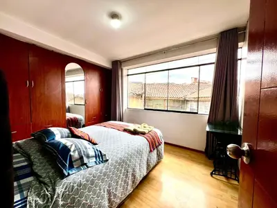 a bedroom with a bed and a large window at Departamento a 5 cuadras de la Plaza de Armas Cusco in Cusco