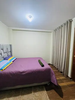 a bedroom with a purple bed and a large window at Departamento 2 Dormitorios, zona tranquila, Ideal 4 Personas El Tambo in Huancayo