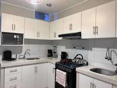 a kitchen with white cabinets and a stove and sink at Misi House Hostal in Lima