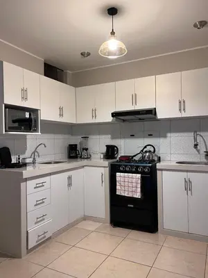 a kitchen with white cabinets and a black stove top oven at Misi House Hostal in Lima
