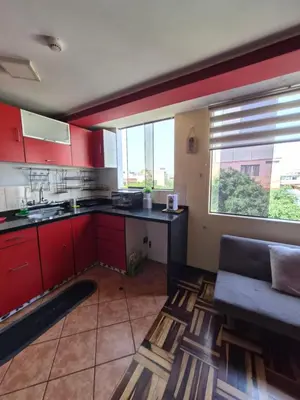 a kitchen with red cabinets and a couch in a room at Apartamento Acogedor, tranquilo y privado in Lima