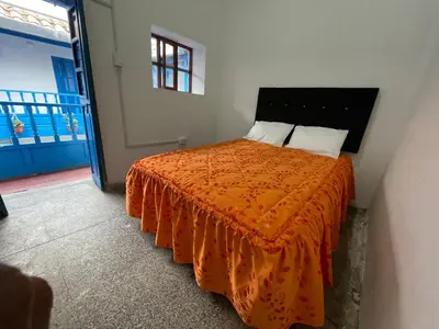 a bedroom with a bed with an orange blanket at Hostel - Cusco Dorms in Cusco
