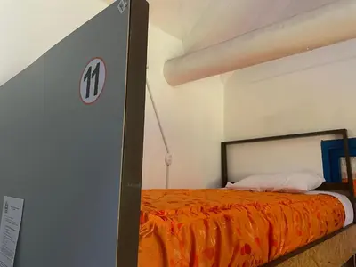 a bedroom with a bed with an orange blanket at Hostel - Cusco Dorms in Cusco