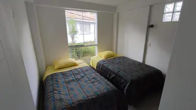 two beds in a room with a window at Apart El Alba III en Centro Historico de Cusco in Cusco