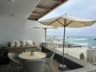 a patio with a table and an umbrella and the beach at Punta Hermosa in Punta Hermosa