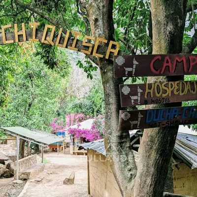 a sign hanging from a tree in a park at Casitas Choquequirao Chikiska in Abancay