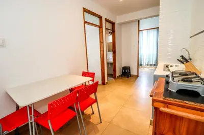 a kitchen with a table and red chairs in a room at CERRO AZUL Alojamiento DUPLEX in Cerro Azul
