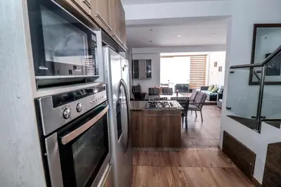 a kitchen with stainless steel appliances and a living room at CERRO AZUL Alojamiento DUPLEX in Cerro Azul