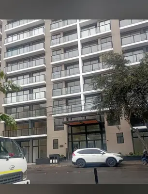 a white car parked in front of a large building at Habitación privada en departamento compartido in Lima