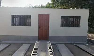 a white building with two windows and a brown door at Casa Conuca in Ica