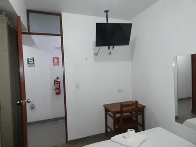 a bathroom with a tv on the wall and a table at Hotel Lima Norte in Carabayllo