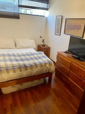 a bedroom with a bed and a dresser with a television at Suite C-1 Wifi 1000 Mbps, recojo gratis aeropuerto in Lima