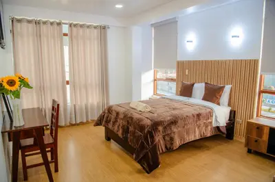a bedroom with a bed and a table and a desk at HOTEL TERRANOVA Abancay in Abancay