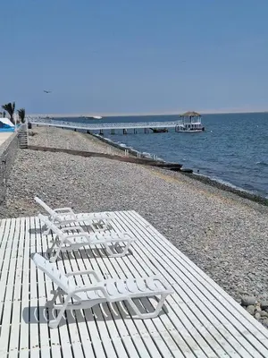 two white chairs sitting on a beach near the water at Paracas Exclusivo Departamento familiar in Pisco