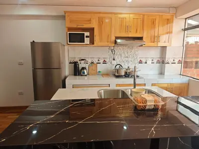 a kitchen with wooden cabinets and a counter top at Refugio Andino Cusco in Cusco