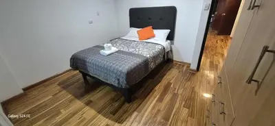 a small bedroom with a bed with an orange pillow at Refugio Andino Cusco in Cusco