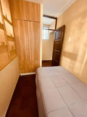 a bedroom with a bed and a wooden cabinet at Estancia Ideal in Lima